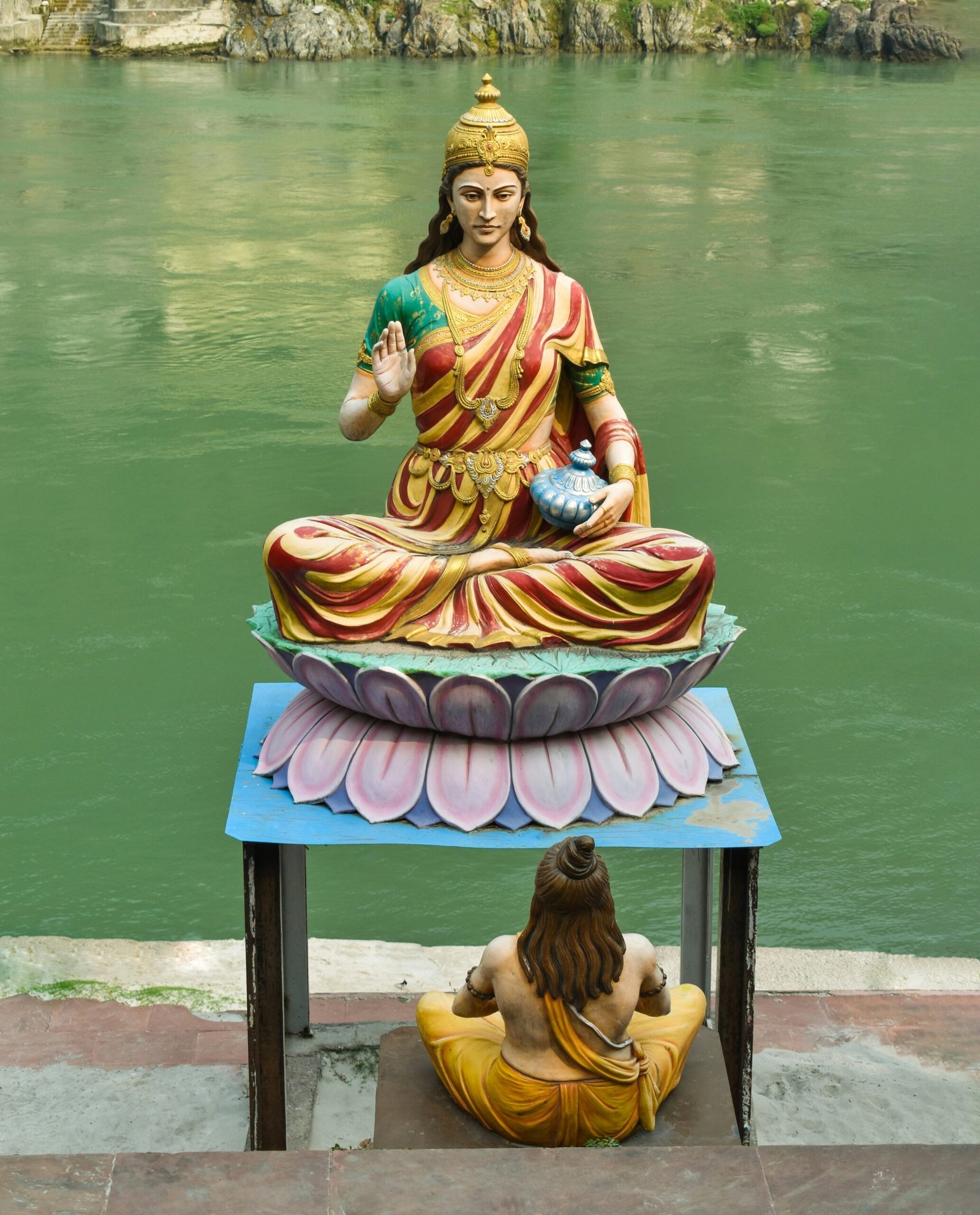 a statue of a buddha sitting on top of a table next to a body of
